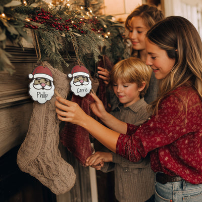 Woman and children hanging stockings with Santa hats and names on a Christmas tree.