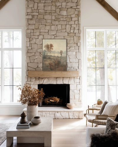 Living room with stone fireplace, large windows, and decorative elements. Autumn Fog wall art print showing misty trees and earthy fall tones in a peaceful landscape setting.