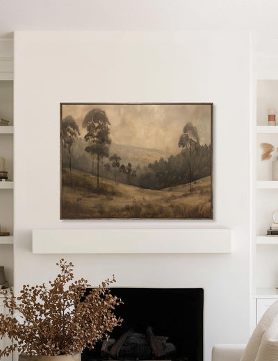 Framed landscape painting above a fireplace in a room with shelves.