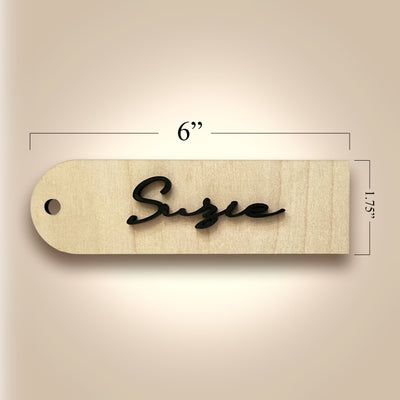 Wooden tag with 'Size' engraving and measurements on a beige background