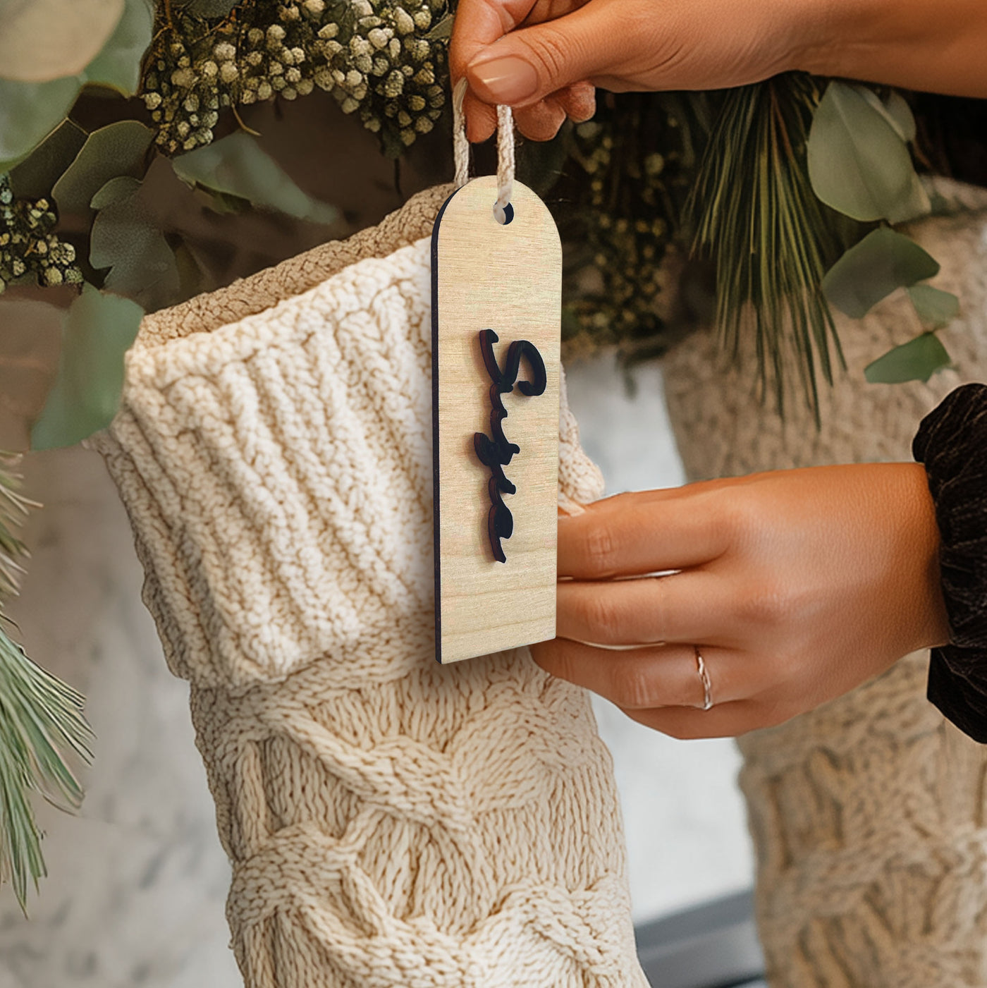"Modern personalized wood stocking tag with custom cut-out vertical name, hanging on a knitted Christmas stocking."