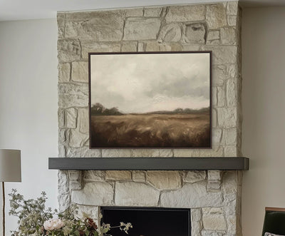 Stone fireplace with a painting above it in a living room setting.