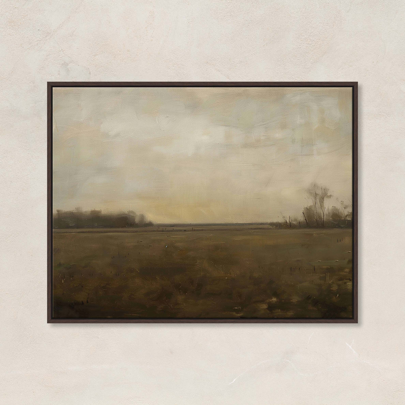 Framed landscape painting of a field with a cloudy sky on a beige wall.