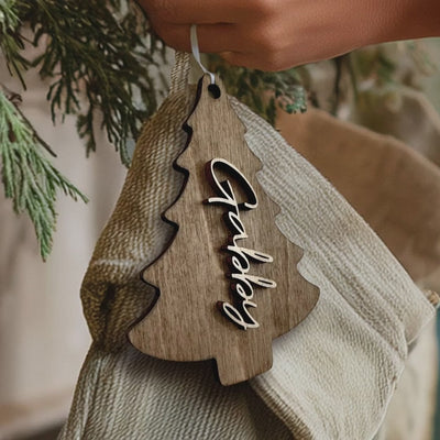 "Personalized wooden Christmas tree tag with custom cut-out name, hanging on a holiday stocking in rustic farmhouse style.